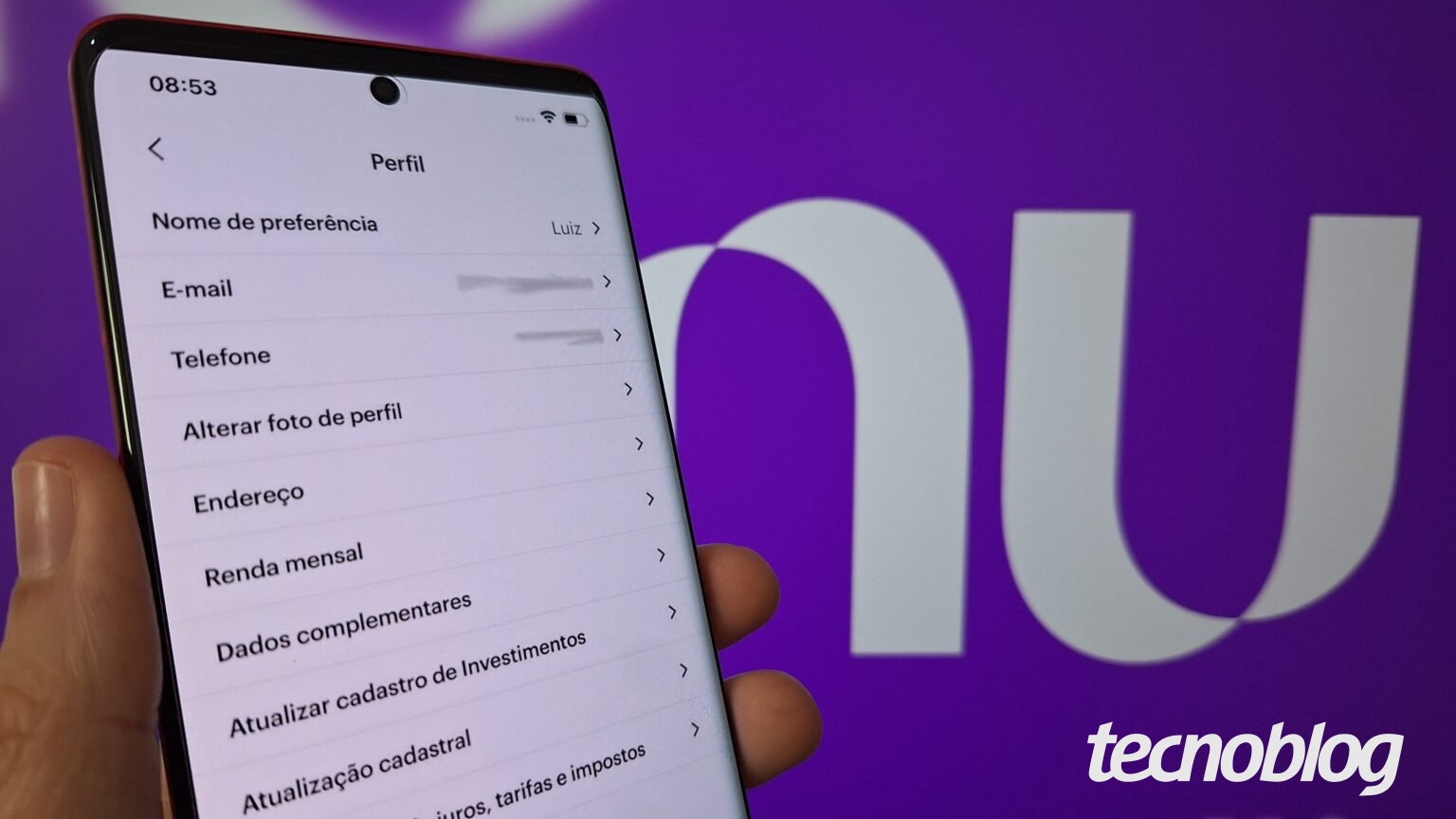 Uma mão segura um celular com o aplicativo do Nubank aberto no menu Perfil