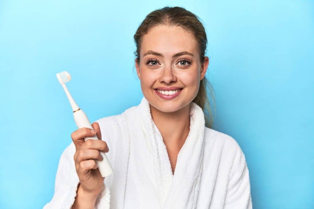 Mulher segurando uma escova de dentes elétrica em um estúdio.