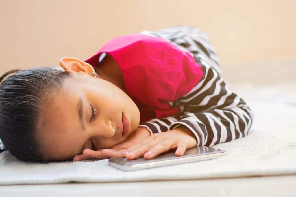 Menina dorme com celular próximo ao corpo