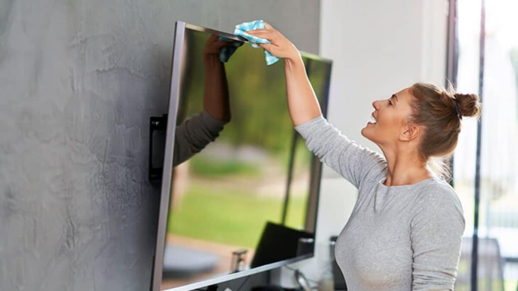 Imagem de uma mulher limpando uma televisão