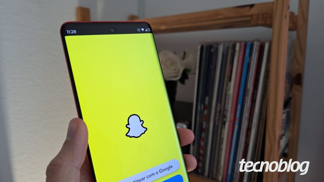 Uma mão segura um celular exibindo a tela inicial do Snapchat