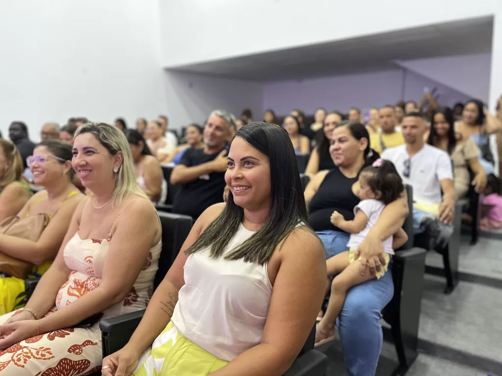 Cerimônia de formatura com alunos sorrindo e familiares presentes