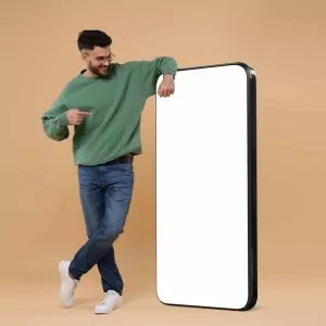 Homem apontando para um enorme celular com a tela vazia em um fundo bege escuro. Mockup para design.