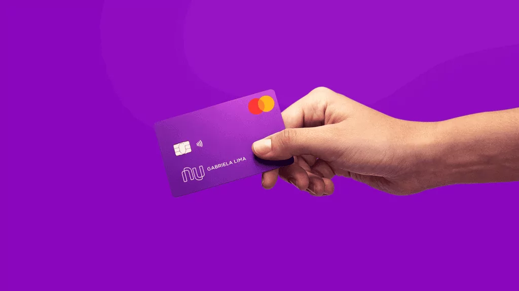 O que é NuScore e como consultar a nota de crédito do Nubank Guia Região dos Lagos 4 Cliente segurando um cartão de crédito do Nubank