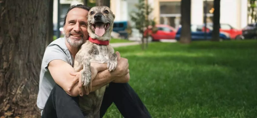 Homem abraçando cachorro (Reprodução: Olezzo/Shutterstock) Homem com cerca de 50 anos abraça cachorro