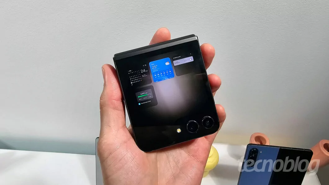 Celular dobrado na mão; tela exibe diversos widgets pequenos